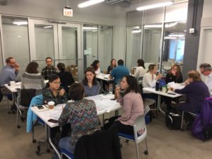 Photo of sustainability coordinators working in small groups at tables